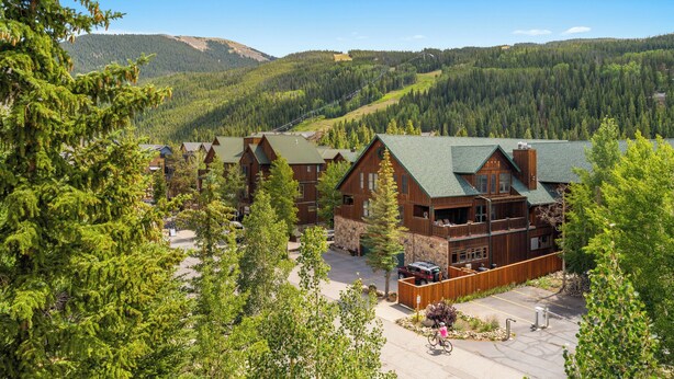 Un chalet comprenant plusieurs cabanes en bois, un espace de stationnement et un paysage montagneux en toile de fond.