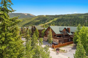 Un chalet doté de plusieurs cabanes en bois, d’un espace de stationnement et surplombant un paysage montagneux.