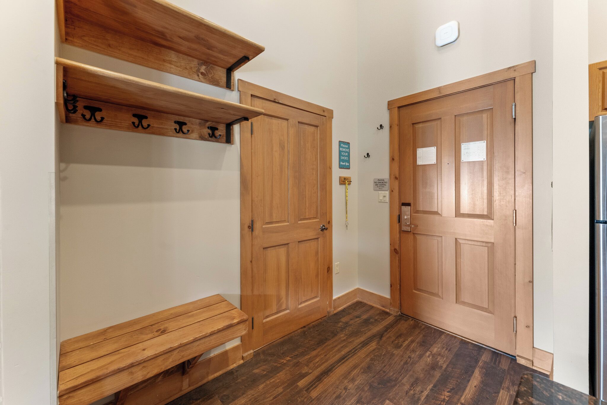 A hallway with wooden doors, a bench, and a coat rack.