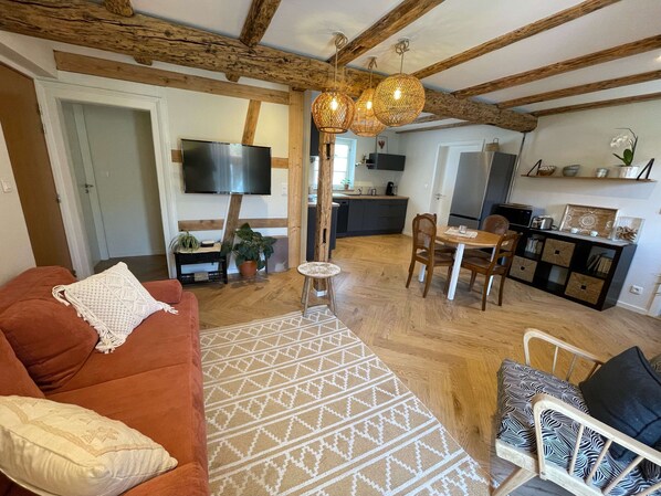 A cozy living room with a sofa, a patterned rug, and a dining area with a table and chairs. - Le Murier:  in the heart of a farmhouse (Mittelhausbergen)