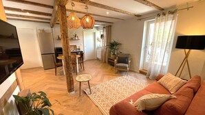 Een woonkamer met een rode bank, houten balken, een eethoek en een keuken.