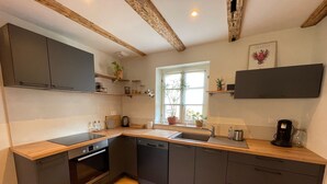 Een moderne keuken met donkere kasten, houten aanrecht en een inbouwoven.
