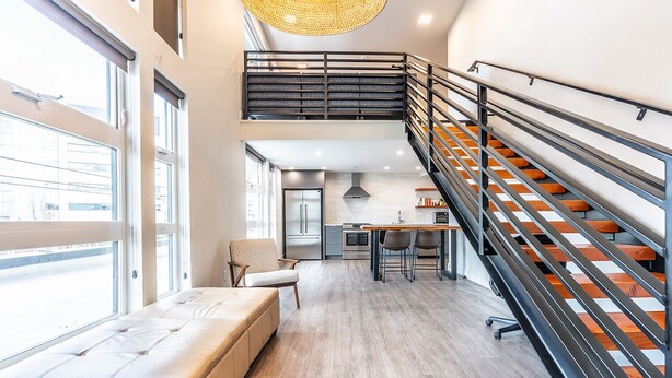 Un intérieur moderne comprenant un escalier, une cuisine et un coin salon avec vue.