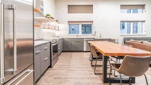Une cuisine moderne équipée d’appareils électroménagers en acier inoxydable, d’une table à manger en bois et d’un four encastré.