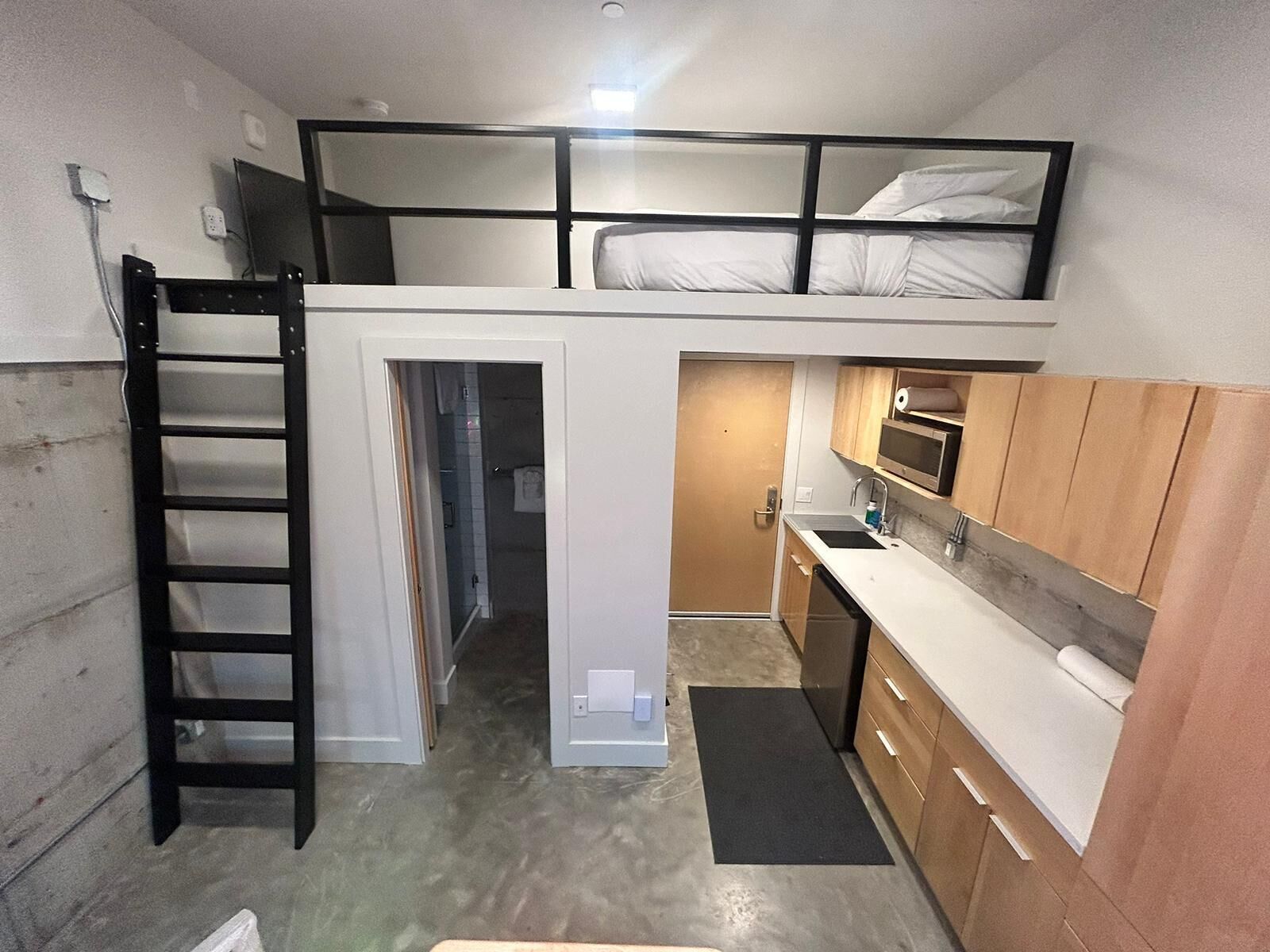 En kompakt lägenhet med ett loft, ett litet kök och ett litet badrum.