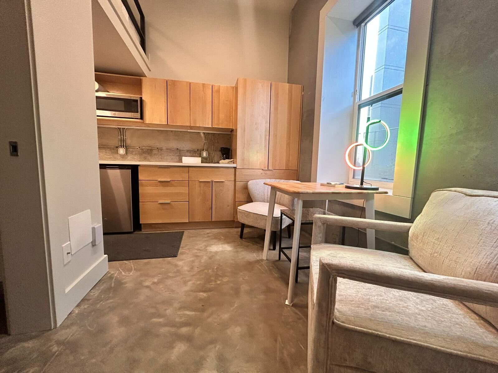 Une cuisine compacte avec des meubles en bois, un four à micro-ondes encastré et un petit coin repas comprenant une table et deux chaises.