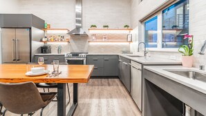 Une cuisine moderne avec des meubles gris, une hotte en acier inoxydable et une fenêtre donnant sur la ville.