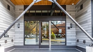 L’entrée d’un hôtel au design moderne, avec une porte en verre et un cadre en métal, donnant sur la rue, et portant l’adresse « 510 Broadway ».