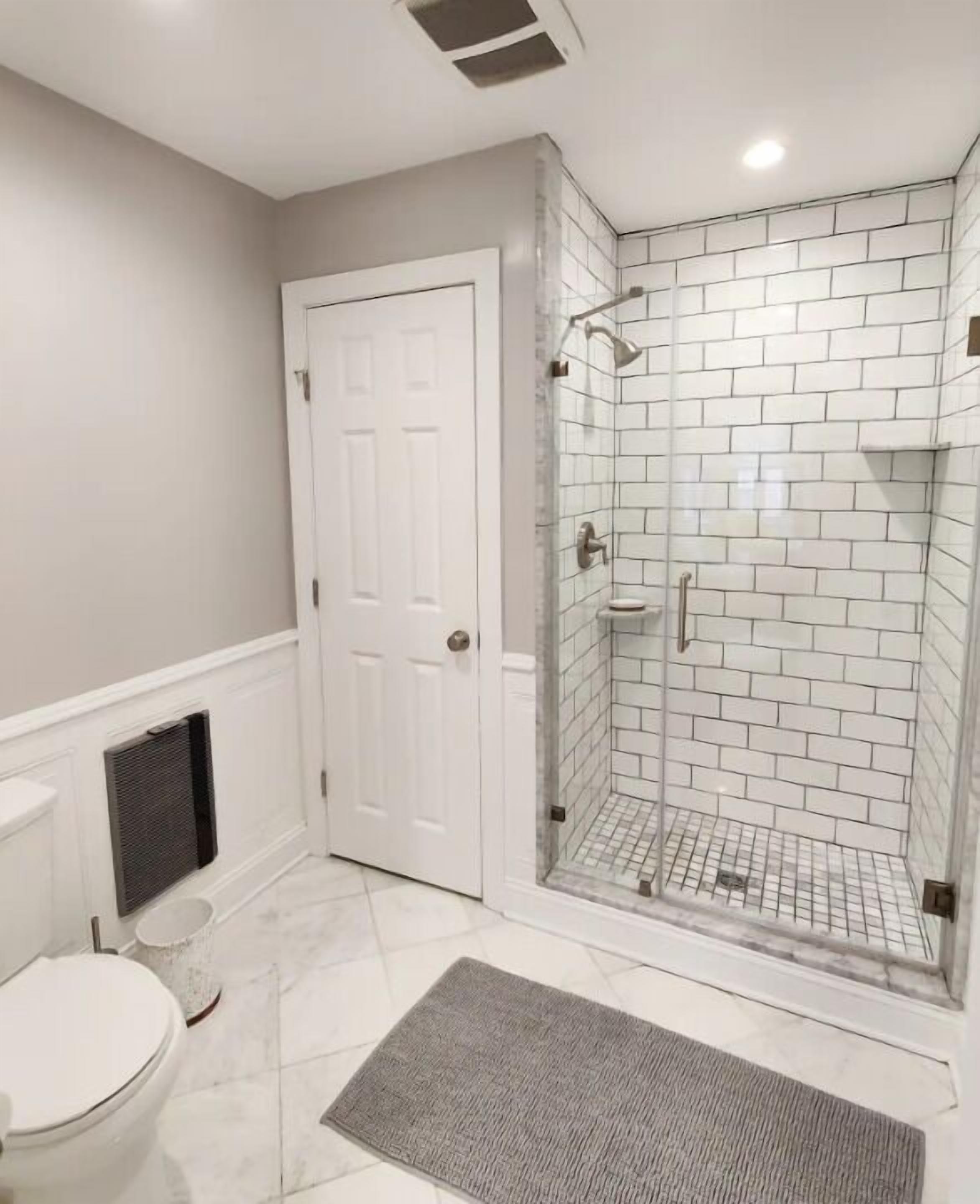 Un bagno con una porta bianca, cabina doccia in vetro e un water bianco.
