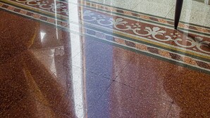 Un sol de marbre poli mène à une porte blanche, ornée d’un rideau blanc.