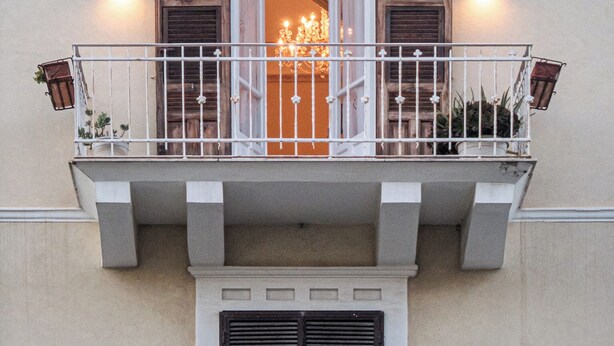 Un balcon avec des volets en bois, un lustre et des appliques murales.