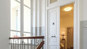 Un escalier avec une main courante en bois et des balustres en métal, menant à une pièce dont la porte est ornée d’un panneau de verre décoratif.