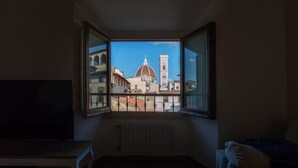 A room with a large window overlooking a historic building with a dome and bell tower.