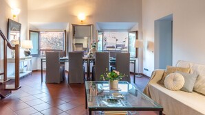A spacious living area with a glass coffee table, a sofa, and a dining area with chairs and a table.