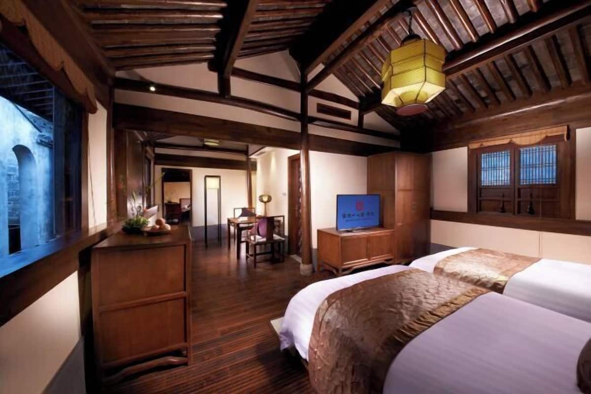 A traditional room with wooden beams, a bed, a desk, and a television.