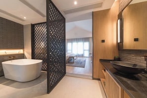 Un baño moderno con una bañera independiente, un tocador de madera y un lavabo grande de color negro.