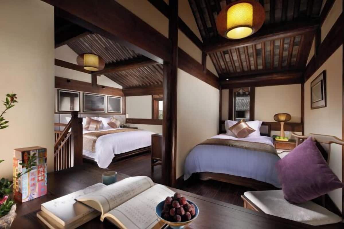 A traditional room with two beds, wooden beams, and a staircase.