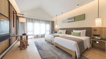 Habitación de hotel moderna con dos camas, un escritorio y un ventanal con cortinas.
