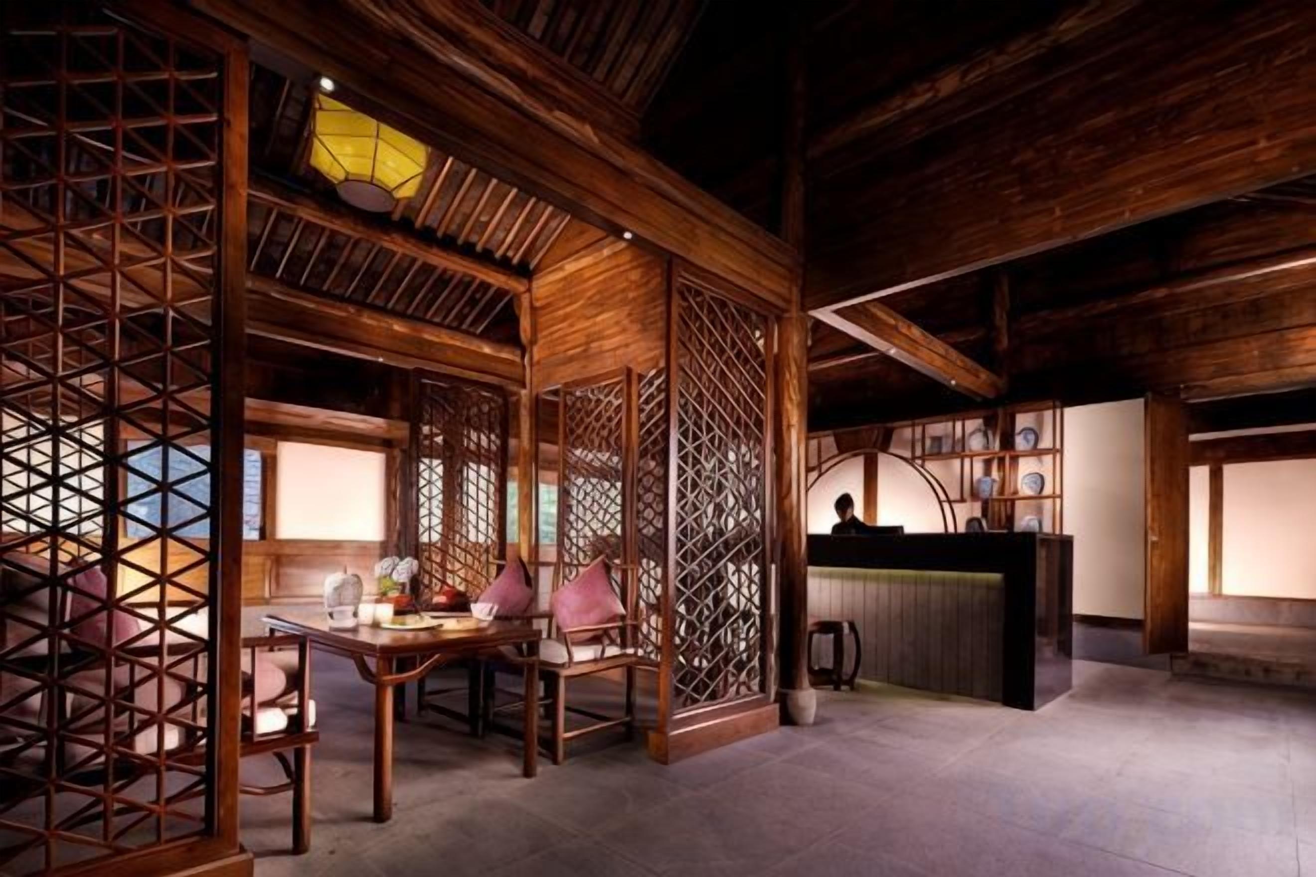 A traditional wooden interior with a dining area, a reception desk, and a view of the outside.