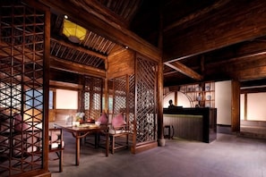 A traditional wooden interior with a dining area, a reception desk, and a view of the outside. - GRAND HOUSE NINGBO (Ningbo)