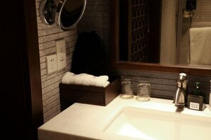 A bathroom with a white sink, a mirror, a towel rack, and a glass container on the counter. - GRAND HOUSE NINGBO (Ningbo)