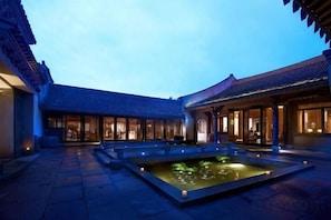 Une cour agrémentée d’un élément aquatique, dotée d’une architecture traditionnelle et d’une galerie couverte.