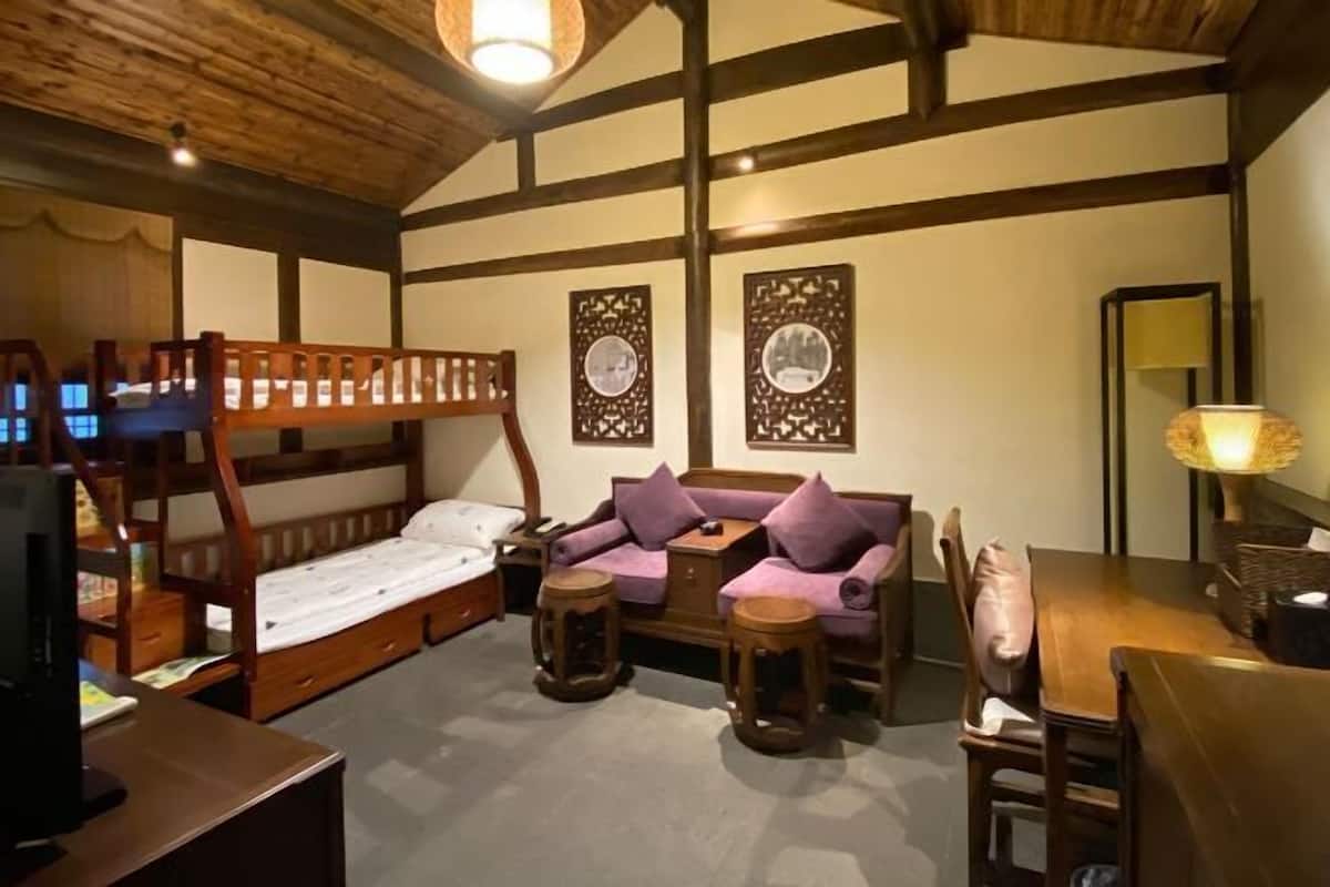A room with a bunk bed, a sofa, a table, and two wall-mounted decorative items.