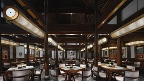 A spacious restaurant with wooden tables and chairs, high ceilings, and decorative lighting fixtures. - GRAND HOUSE NINGBO (Ningbo)