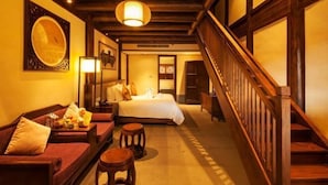 A hotel room with a wooden staircase, a bed, a sofa, and a small table with a lamp. - GRAND HOUSE NINGBO (Ningbo)