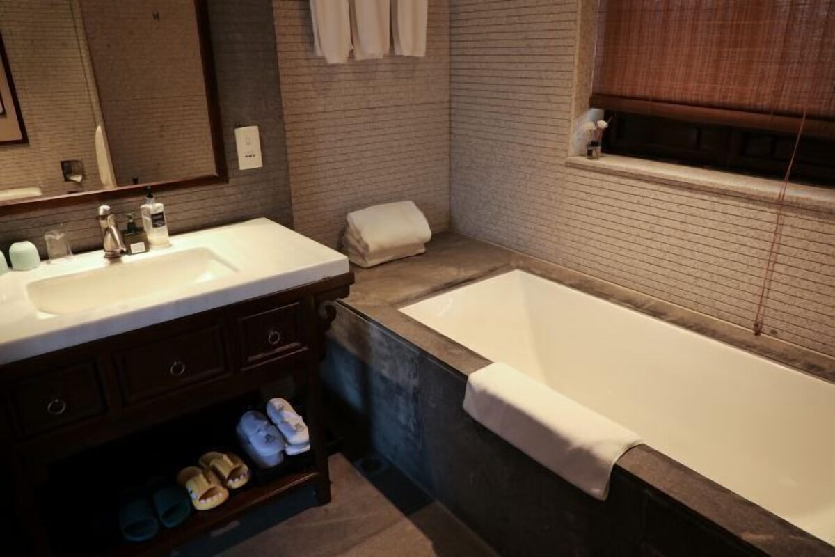 Een moderne badkamer met een groot bad, een wastafel met twee kommen en een handdoekrek.