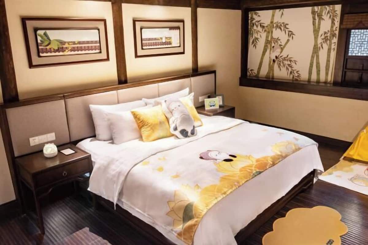A hotel room with a bed, nightstands, a window with a view, and framed artwork on the wall.