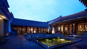 A courtyard with a water feature, traditional architecture, and a well-lit entrance. - GRAND HOUSE NINGBO (Ningbo)