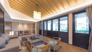 Una sala de estar moderna con techo de madera, ventanas amplias, un sofá, una mesa de comedor y sillas.