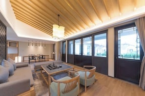 Una sala de estar moderna con techo de madera, ventanas amplias, un sofá, una mesa de comedor y sillas.