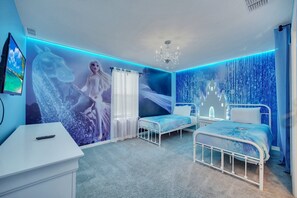 Relax in a stylish bedroom with a comfortable white bed, a bedside table, and a dresser, surrounded by a beautiful winter mural.