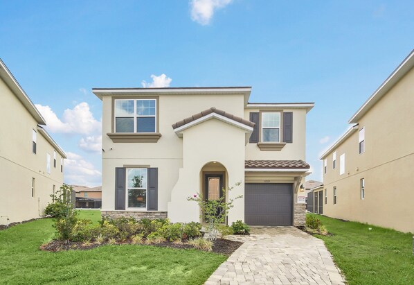 Stunning two-story home with a central entrance, flanked by windows and a garage door.