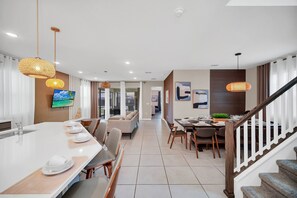 Enjoy dining and relaxation in this inviting space with a spacious island, comfortable seating area, and staircase leading to an upper level.