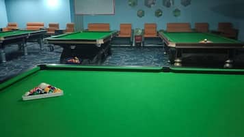 A pool table with balls, a billiard cue, and a pool table with a green felt surface.