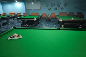 Une table de billard avec des billes, une queue de billard et une table de billard recouverte d’un drap vert.