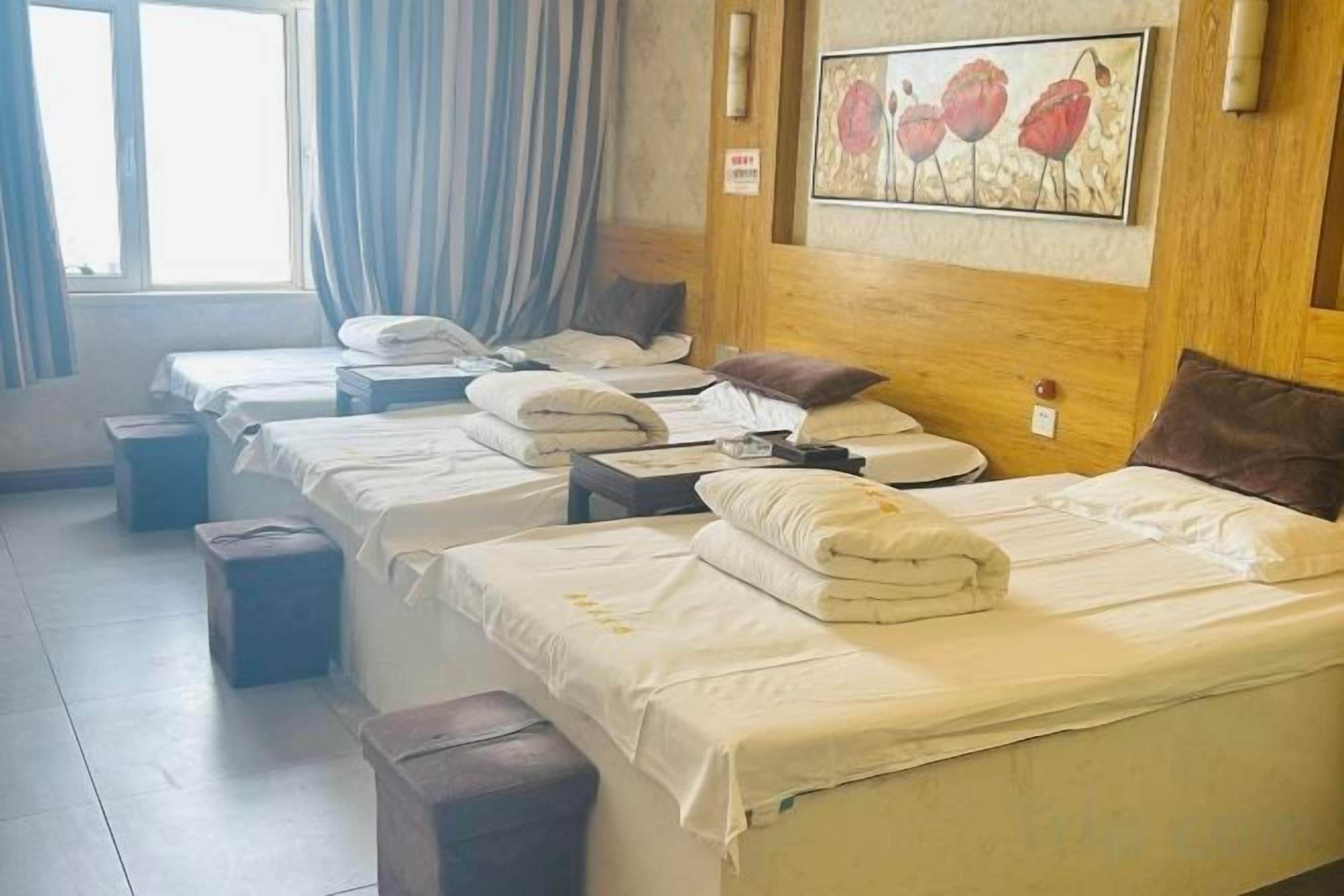 A hotel room with multiple beds, a wooden headboard, and a painting on the wall.
