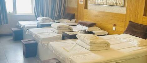 A hotel room with multiple beds, a wooden headboard, and a painting on the wall.