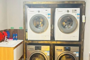 Un cuarto de lavandería con dos lavadoras de carga frontal y dos de carga superior.