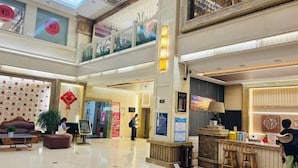 A spacious lobby with a checkered floor, a reception desk, and seating areas. - Jiangsu Hotel (Yining City)