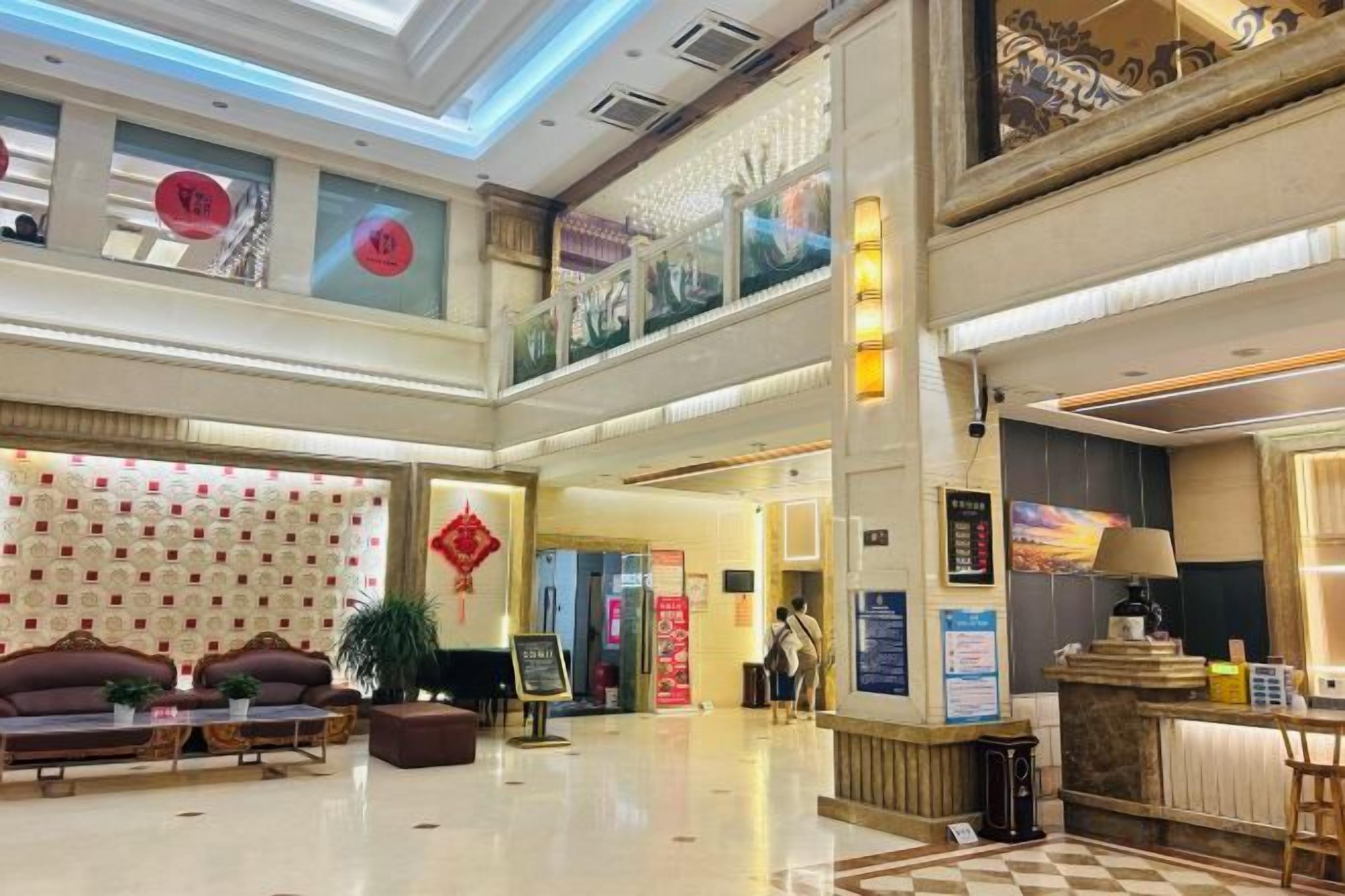 A spacious lobby with a reception desk, seating area, and a staircase leading to an upper level.