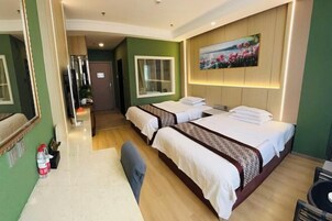 Habitación de hotel con dos camas, un espejo grande, un cuadro en la pared y una mesita con una silla.