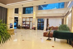 A spacious lobby with a reception desk, seating area, and a staircase leading to upper floors.