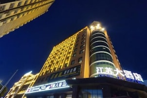 Un hotel alto con señalización iluminada, varios pisos y una entrada destacada.