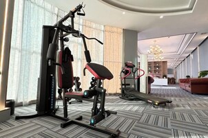 A gym with exercise equipment, a treadmill, and a lounge area with a sofa and a desk.