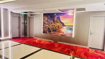 A hotel lobby with a red carpet, a mural of a lighthouse, and a white door.
