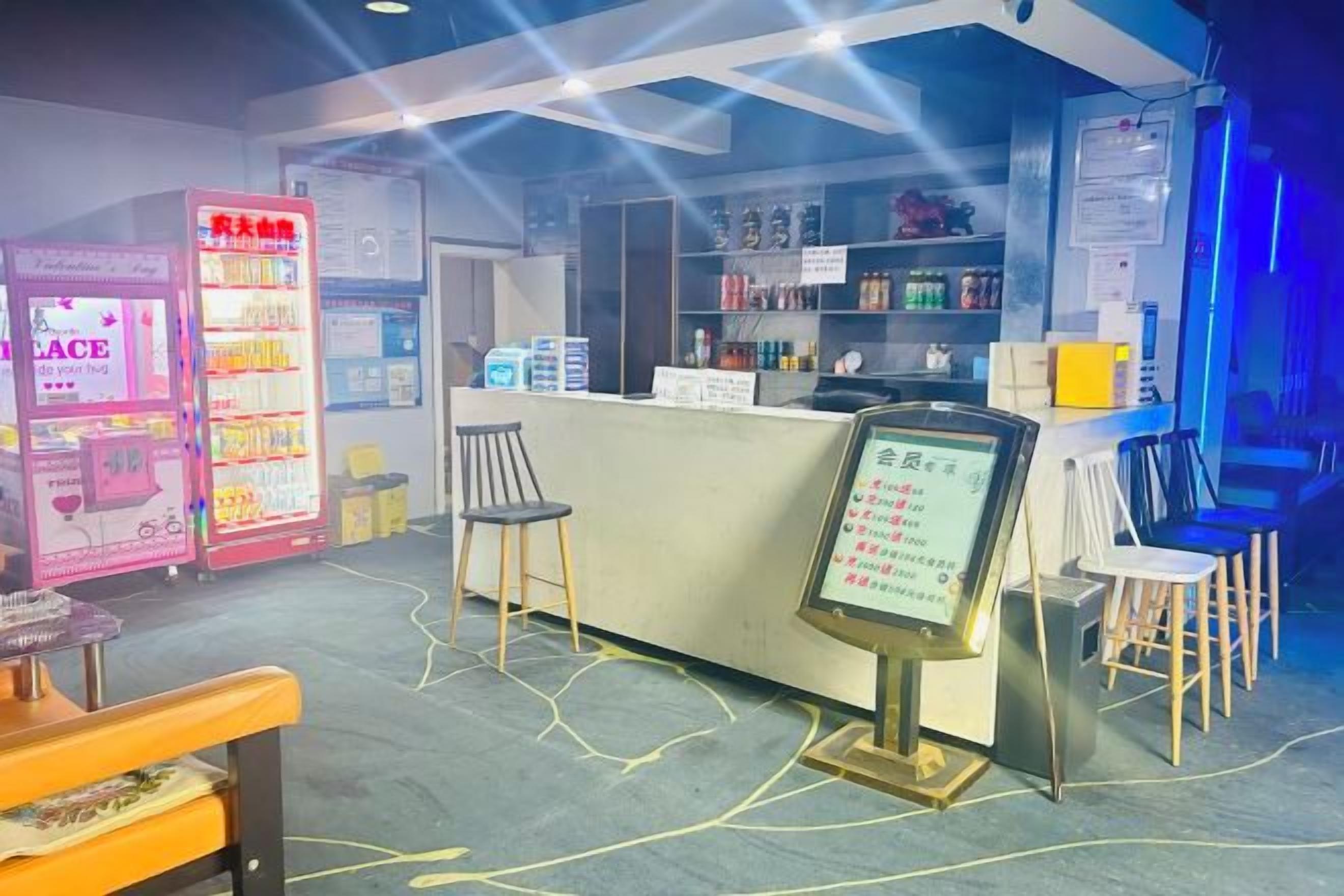 A bar area with a counter, stools, and a neon sign.